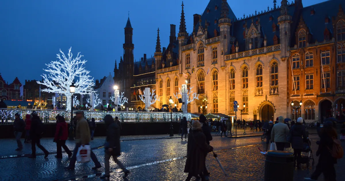 Winter date ideas: the Christmas market and ice rink lit up on the Grote Markt in Bruges at dusk